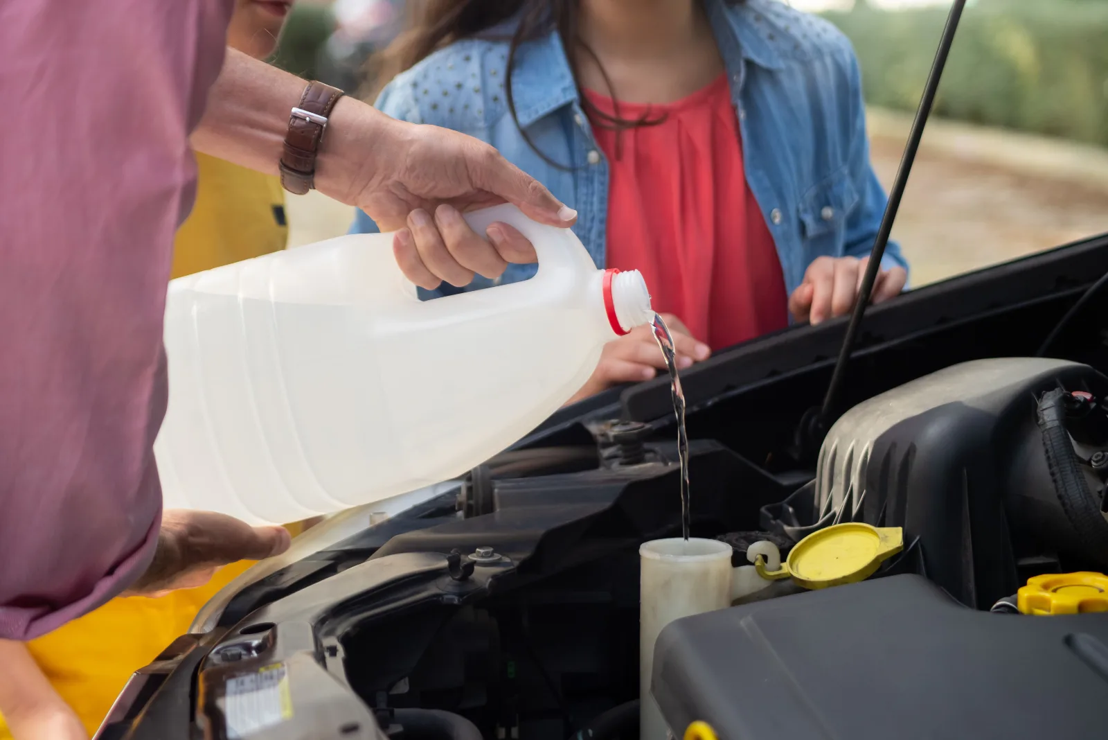 Technician topping up a car AdBlue tank with genuine fluid