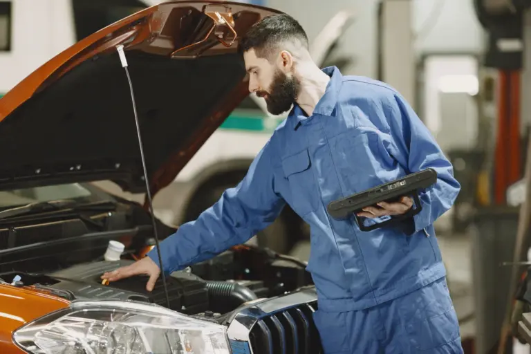 Technician inspecting a petrol car engine after a diesel in petrol misfuelling