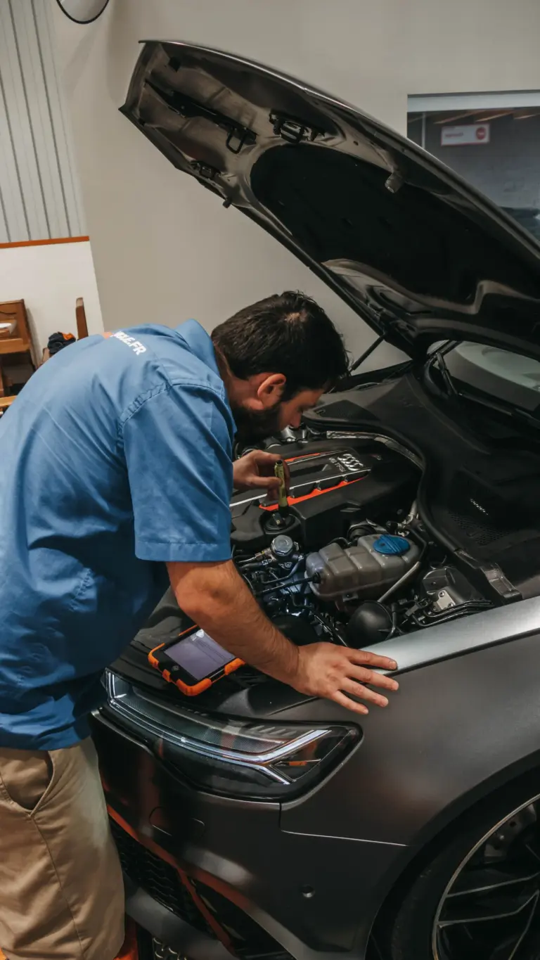 Technician inspecting a diesel car engine after an unleaded petrol misfuelling